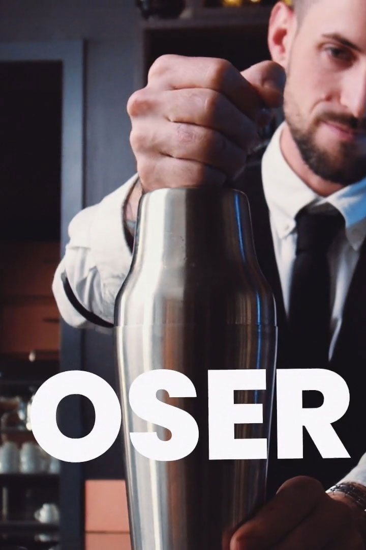Barman préparant un cocktail avec le mot 'Oser' écrit en blanc.
