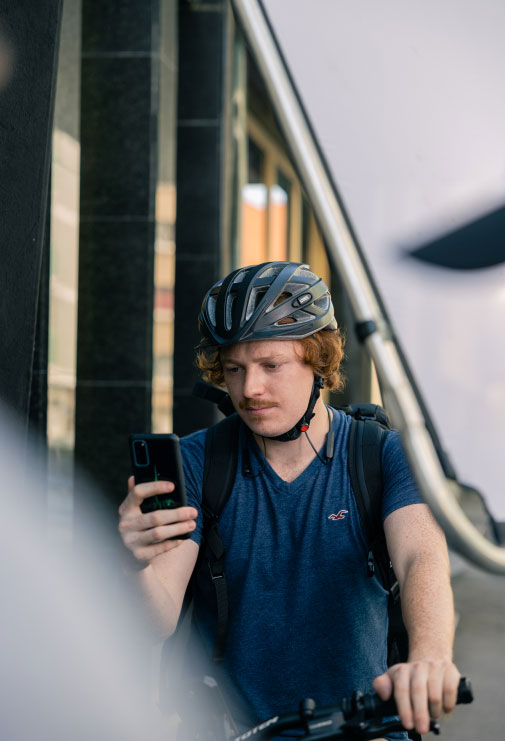 Young men riding a bike while looking at his phone